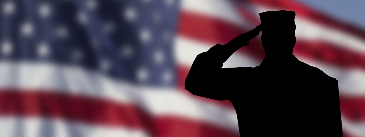 美国国旗在后台轮廓的一个士兵在前台向国旗行礼